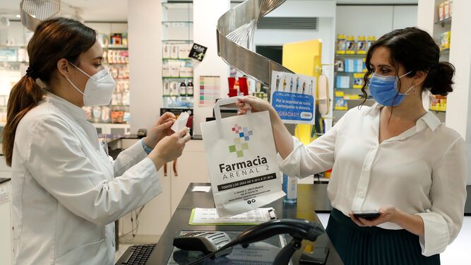 La presidenta de la Comunidad de Madrid, Isabel Díaz Ayuso, retira su medicación tras utilizar su Tarjeta Sanitaria Virtual en una farmacia de la capital, este lunes, durante la presentación de la aplicación.