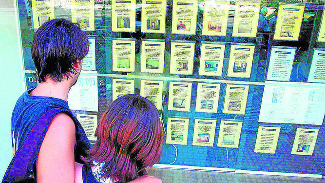 Una pareja observa anuncios de venta y alquiler de inmuebles.