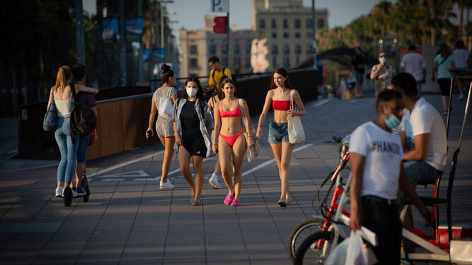 Varias jóvenes en el paseo de la Barceloneta sin mascarilla pese a la obligación de tener que llevarlas.