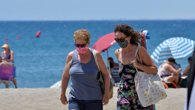Dos mujeres abandonan la playa con la mascarilla puesta.
