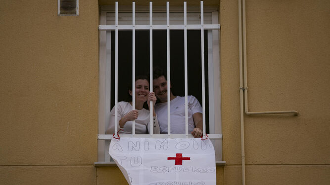 Una pareja muestra una pancarta de apoyo a los sanitarios durante el confinamiento general.