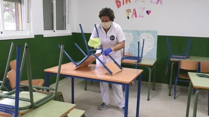 Una trabajadora municipal limpia el aula de un colegio público.