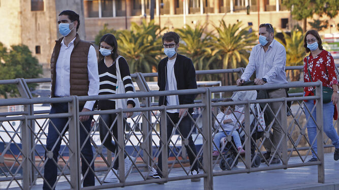 Varios paseantes con mascarilla por el puente de San Telmo.
