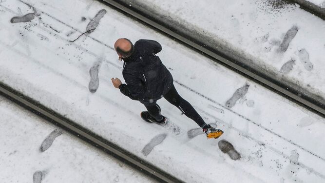 Un hombre corre por una calle totalmente nevada.
