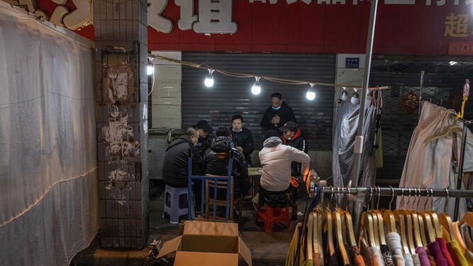 Un grupo de hombres juega a las cartas en un mercado nocturno en Wuhan.