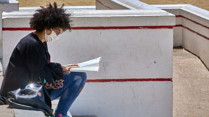 Una mujer lee un libro en la Playa de la Victoria, en Cádiz.