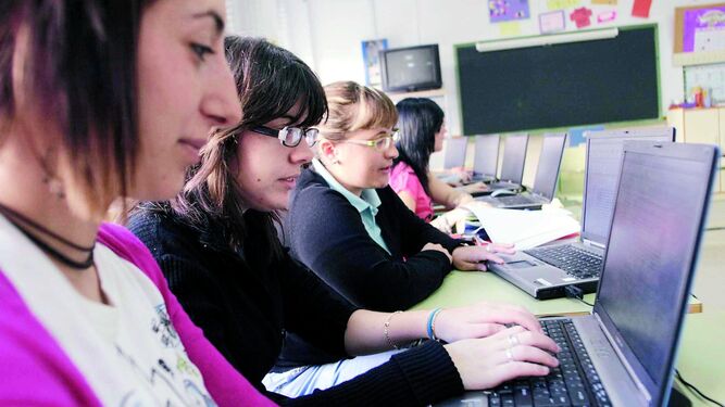 Alumnos con ordenadores en su colegio.