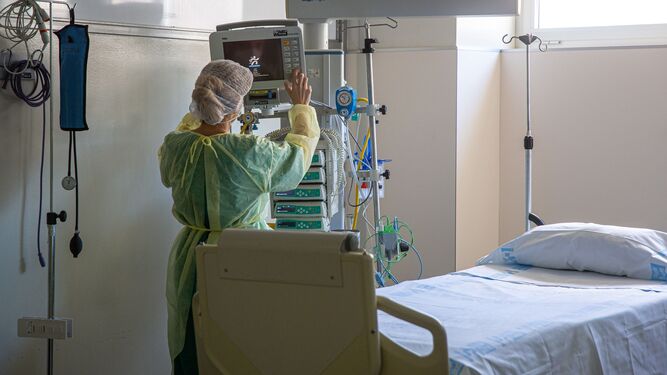 Una sanitaria regula el monitor de control en un box de UCI de un hospital.