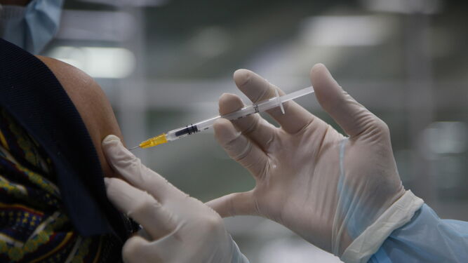 Un sanitario inocula una vacuna a un paciente