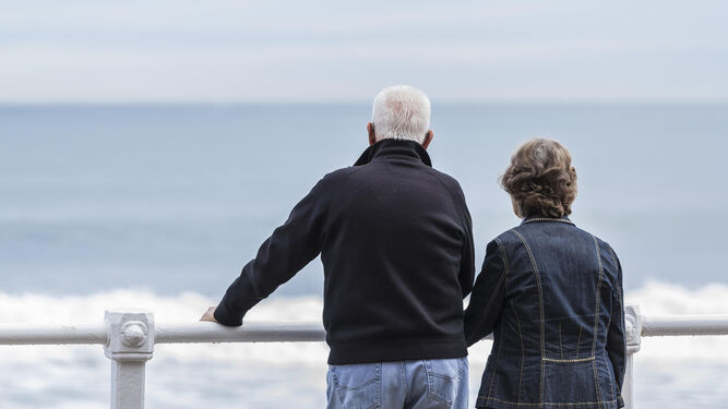 Dos personas mayores contemplan el mar.