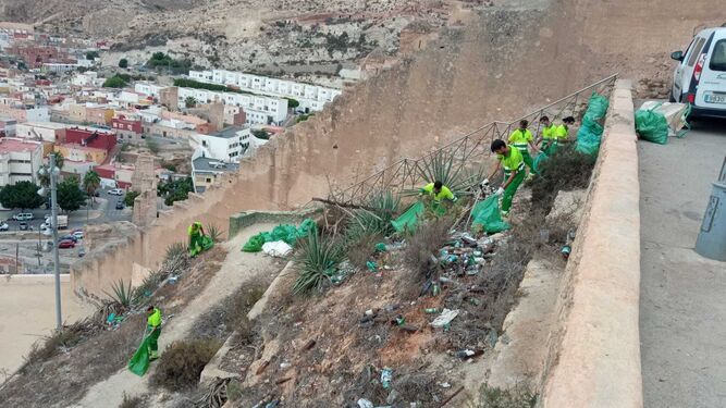 Operarios de la empresa de parques y jardines retiran los residuos acumulados en la ladera sur de la Alcazaba