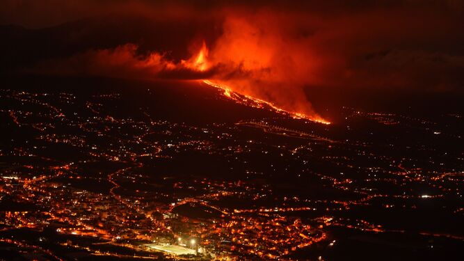 Imagen de la zona de El Paso iluminada durante la noche, con el volcán en erupción al fondo