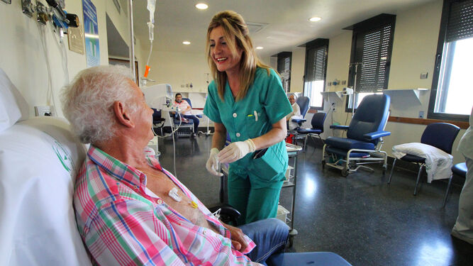 Una profesional charla distendidamente con un paciente que recibe el tratamiento en una Unidad de Oncología.
