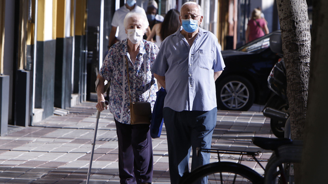 Dos ancianos con mascarilla pasean por una calle de Sevilla.