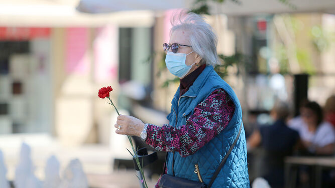 Una señora pasea con una flor comprada en la capital de Almería.