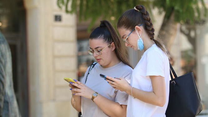 Dos jóvenes almerienses consultan su teléfono en una calle de la capital.