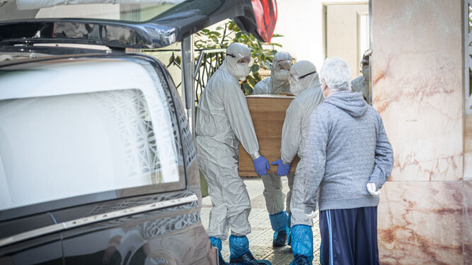 Sanitarios trasladan a un fallecido por coronavirus durante su funeral.