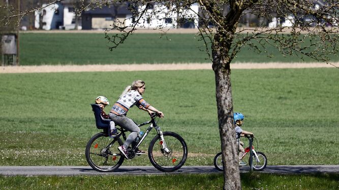 Una mujer lleva a su hijo menor de siete años en un asiento acoplado sobre su bicicleta