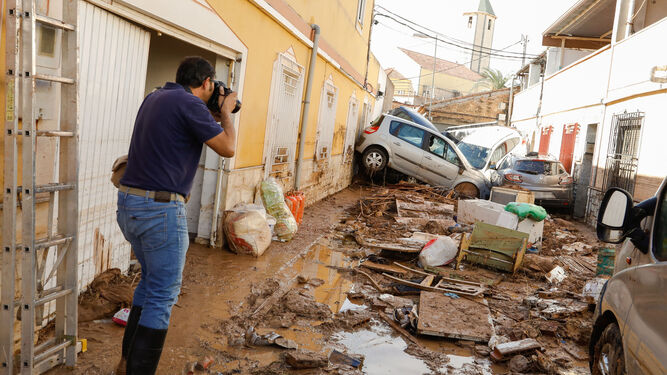 Un fotógrafo capta una imagen de una calle con vehículos amontonados tras la inundación en la pedanía de Javalí Viejo (Murcia).