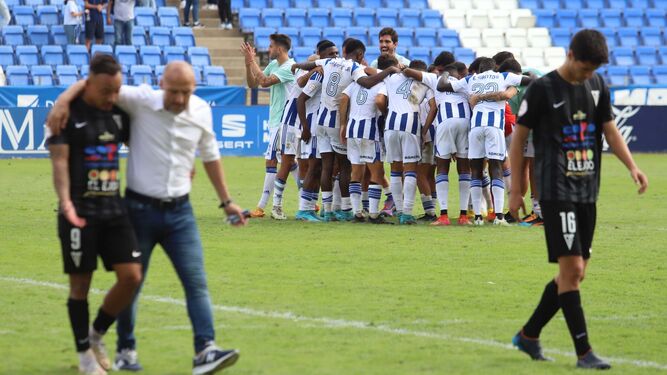 David Cabello consuela a Juancho al término del partido en Huelva, mientras el equipo local celebra su victoria lograda in extremis