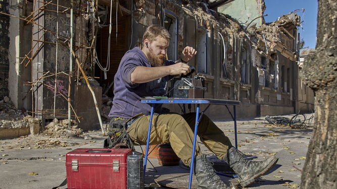 Un especialista intenta reparar la fibra óptica ante un edificio administrativo destruido en Jarkov.