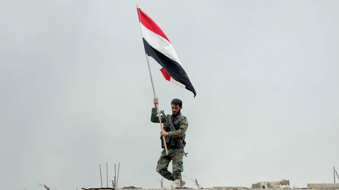 Un soldado del Ejército sirio con una bandera del país.
