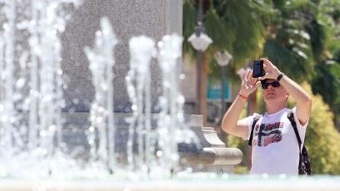 Un hombre sostiene el teléfono móvil con sus dos manos mientras toma una fotografía.