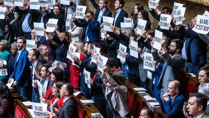Diputados franceses muestran carteles con el lema 'No a los 64 años' en la Asamblea Nacional.