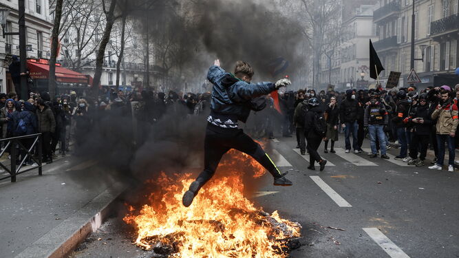 Un manifestante salta sobre el fuego durante la protesta contra la reforma de las pensiones en París.