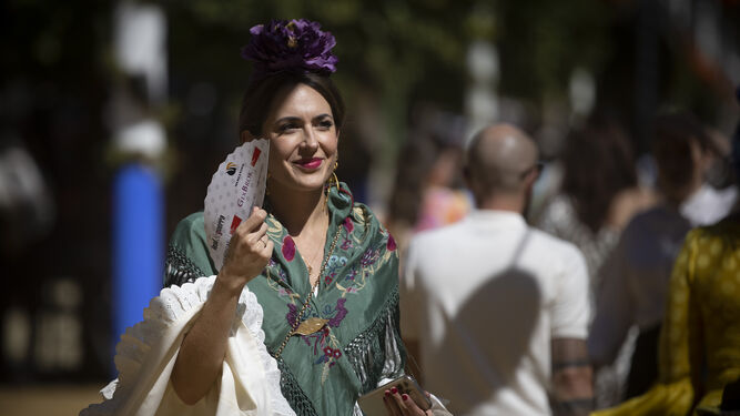 Una mujer vestida de flamenca, a pleno sol, en el real de la Feria.