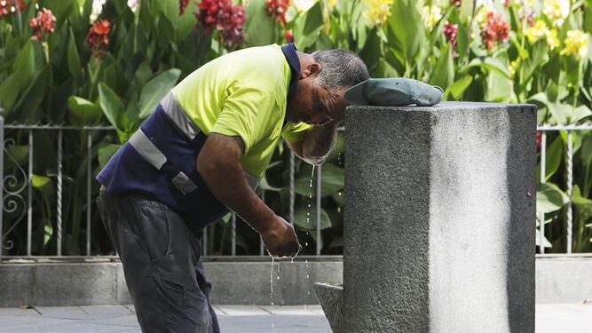 Un trabajador se refresca en una fuente de Sevilla.