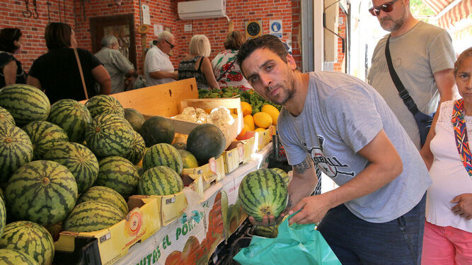 Paco muestra un ejemplar de sandía delante de su frutería,  junto al Mercado de Los Ángeles