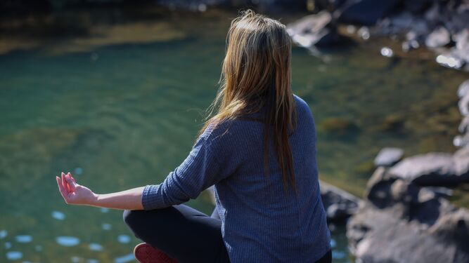 Una mujer medita junto a una cascada
