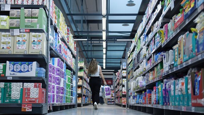 Una joven carga con varios artículos mientras realiza la compra en un supermercado.