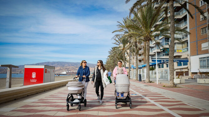 Varias mujeres caminan junto a sus pequeños por el Paseo Marítimo de Almería.