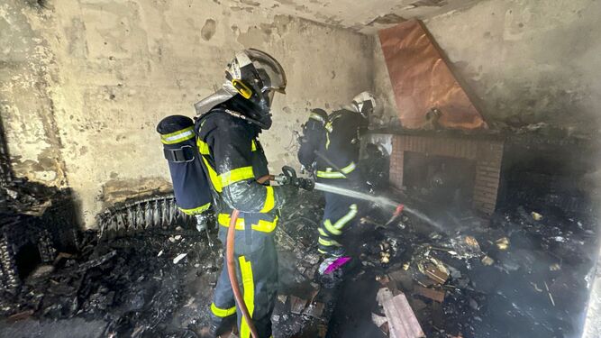 Varios bomberos sofocan un aparatoso incendio en el interior de una vivienda.