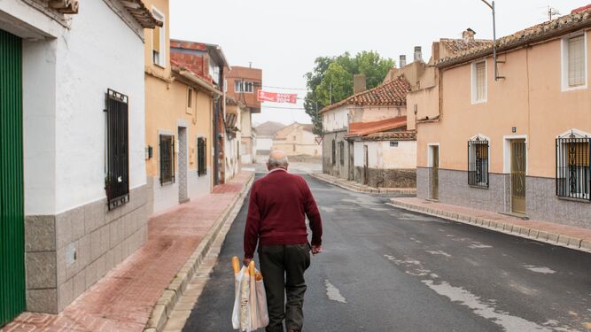Un hombre camina hacia su hogar tras comprar en pan en una calle vacía.