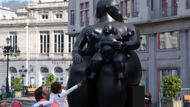 Una niña señala al niño de la estatua de 'La Maternidad' de Botero en la plaza de la Escandalera de Oviedo.