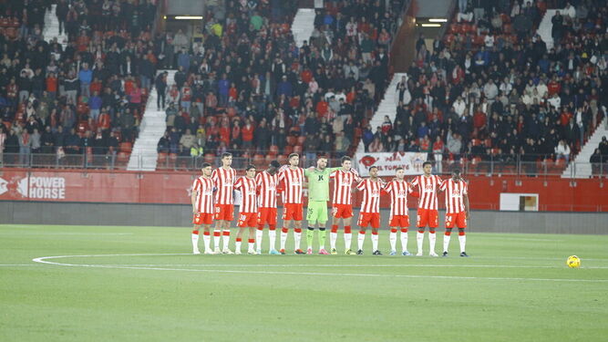 El equipo, con la afición al fondo, durante el minuto de silencio ante el Atlético