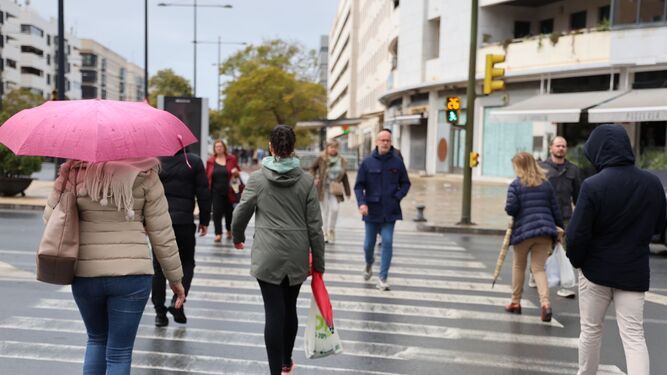 La gente pasea con paraguas y chubasqueros por Huelva.